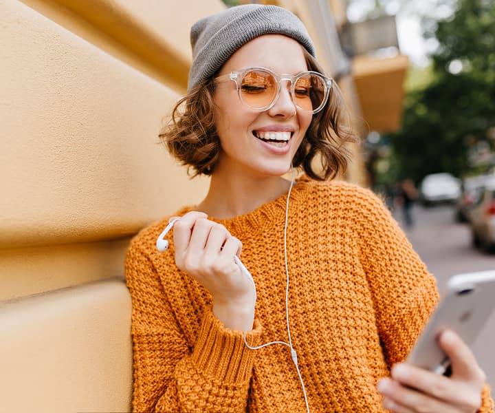 A woman happily watches her phone